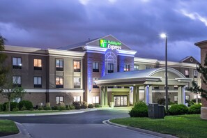 A Holiday Inn Express hotel with a brick facade, a covered entrance, and a well-maintained lawn. - Holiday Inn Express - Village West (Kansas City)