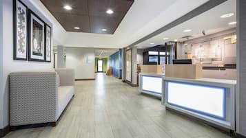 A hotel lobby with a reception desk, seating area, and framed artwork on the walls.