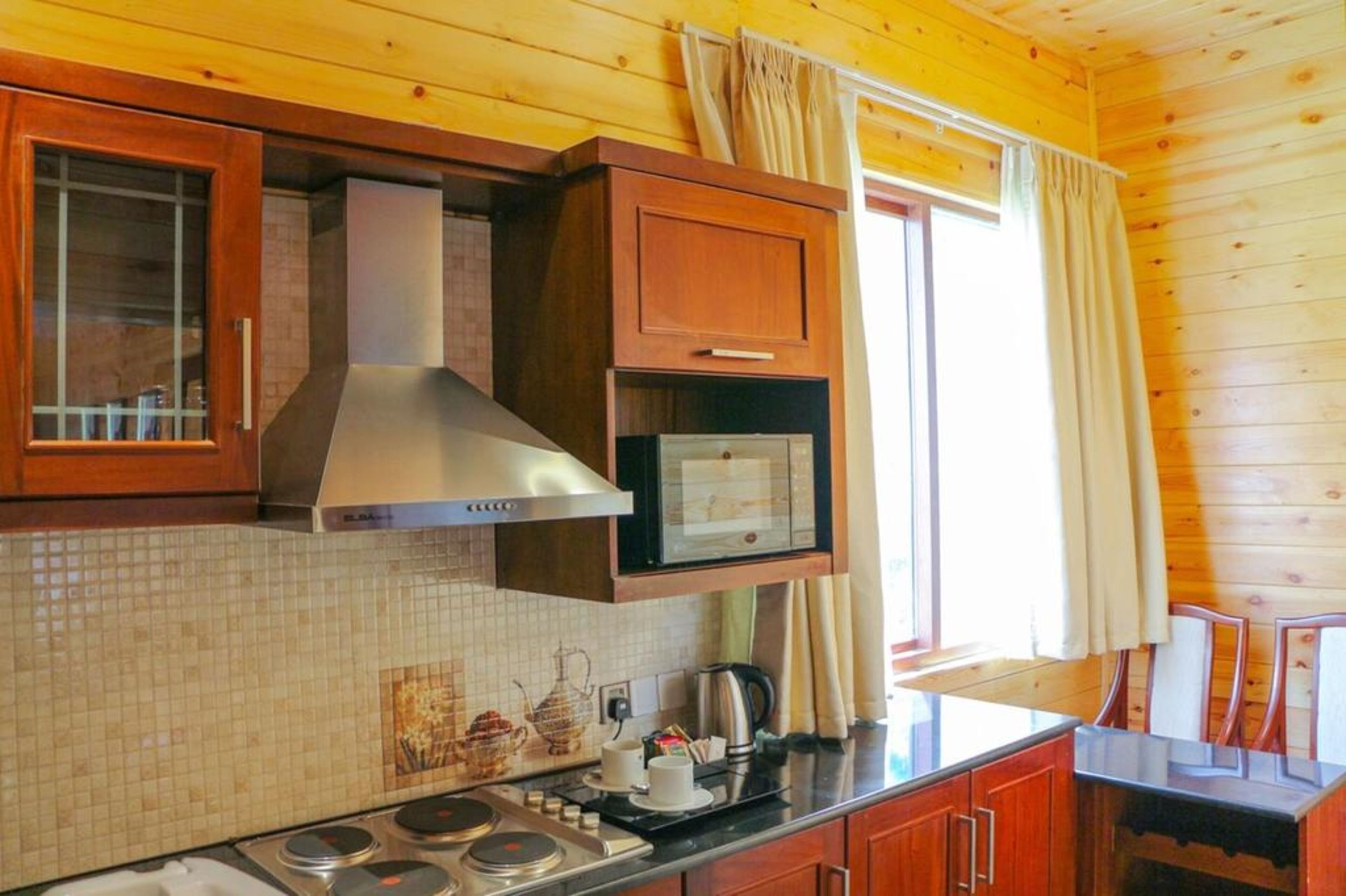 A kitchen with wooden cabinets, a microwave, a stove, and a tiled backsplash.