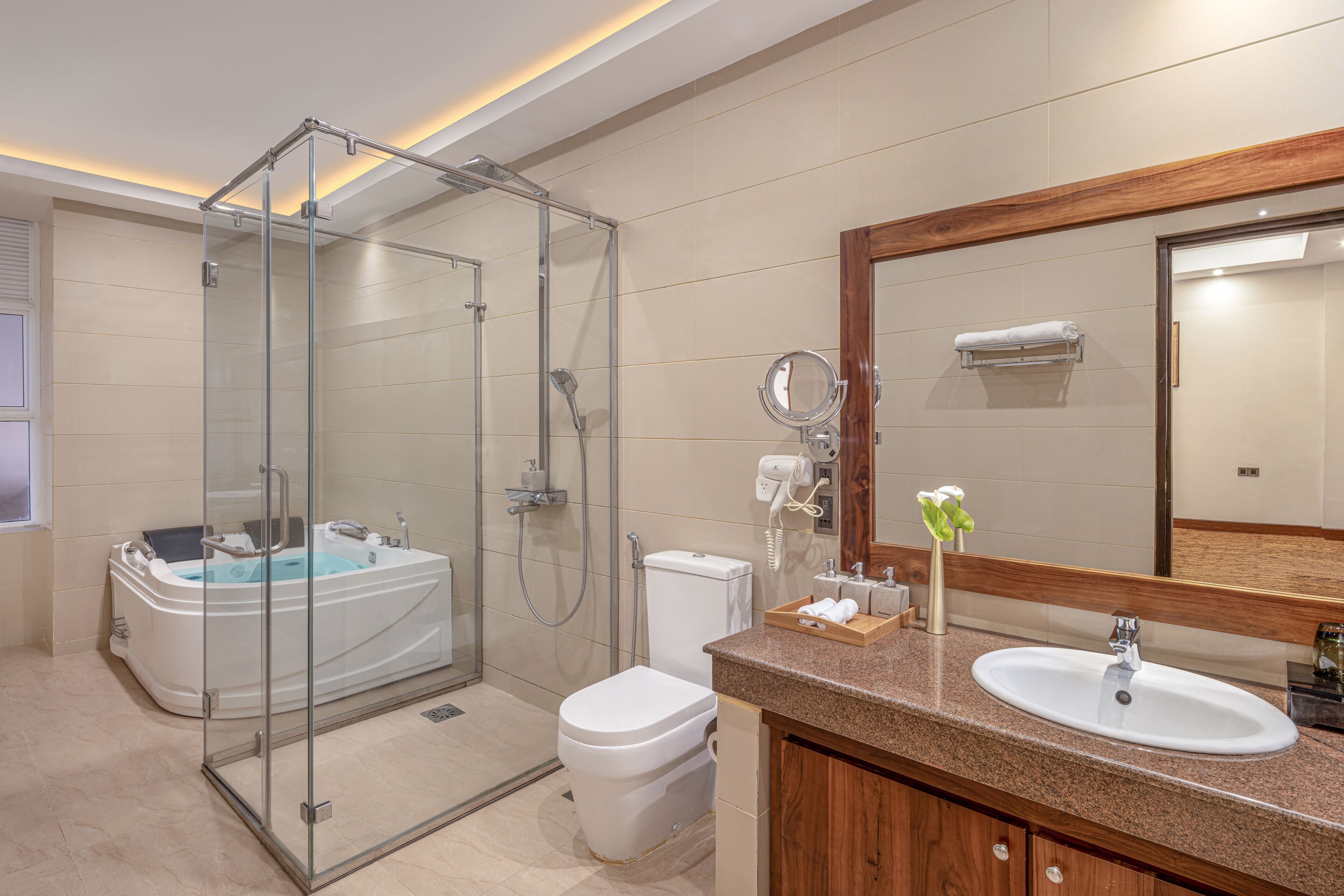 Un baño moderno con ducha de vidrio, bañera independiente, inodoro y tocador con lavamanos y espejo.