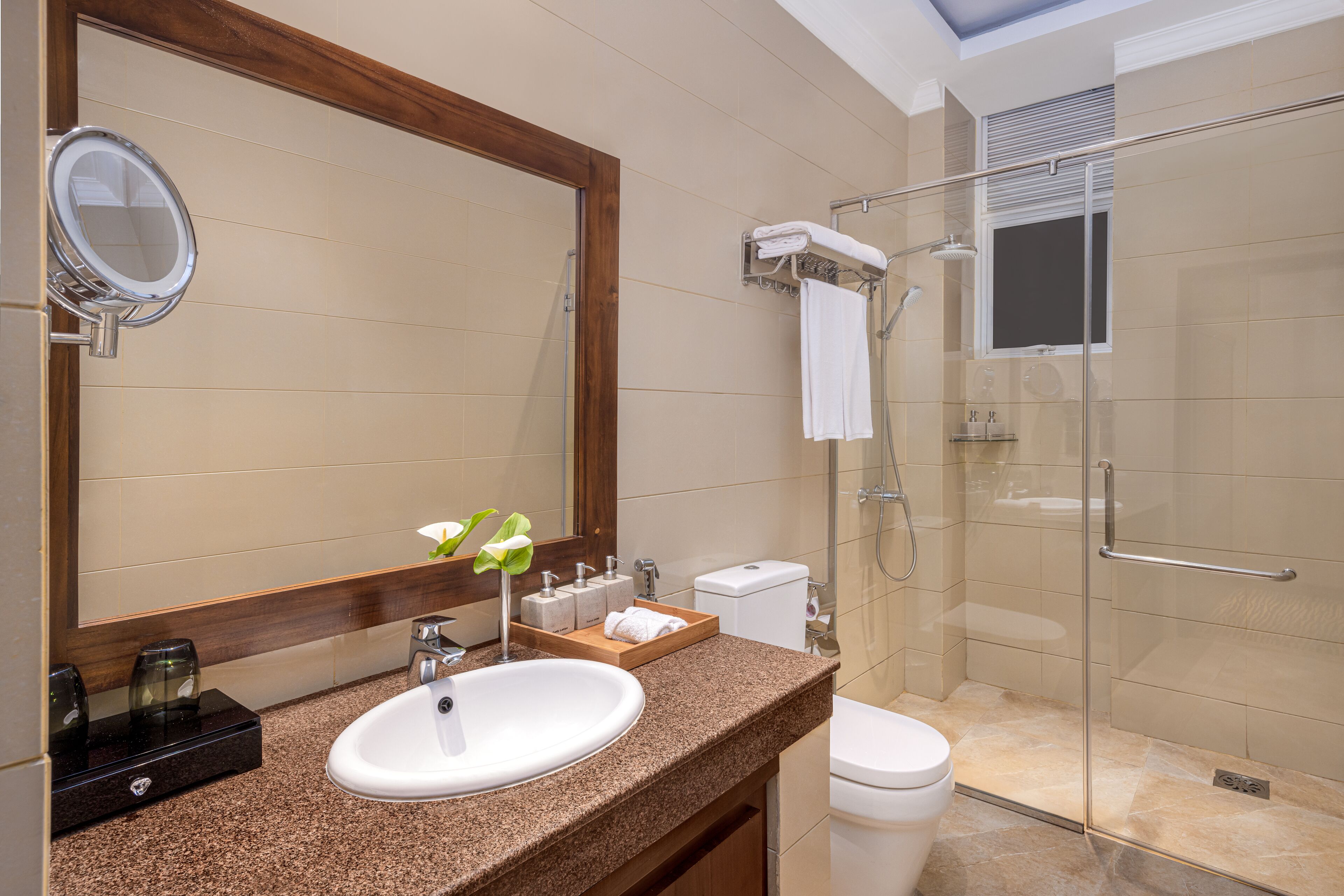 A modern bathroom with a granite countertop, a white sink, a large mirror, and a glass-enclosed shower.