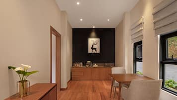 Una cocina moderna con armarios de madera, una mesa de comedor y sillas. Hay un jarrón con flores blancas sobre una consola de madera.