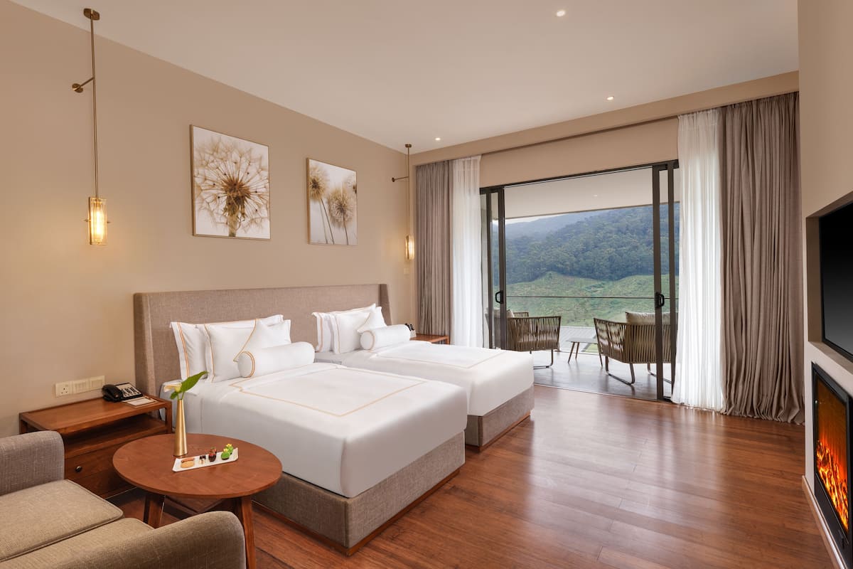 A hotel room with two beds, a TV, a fireplace, a balcony with a view, and a dining area.