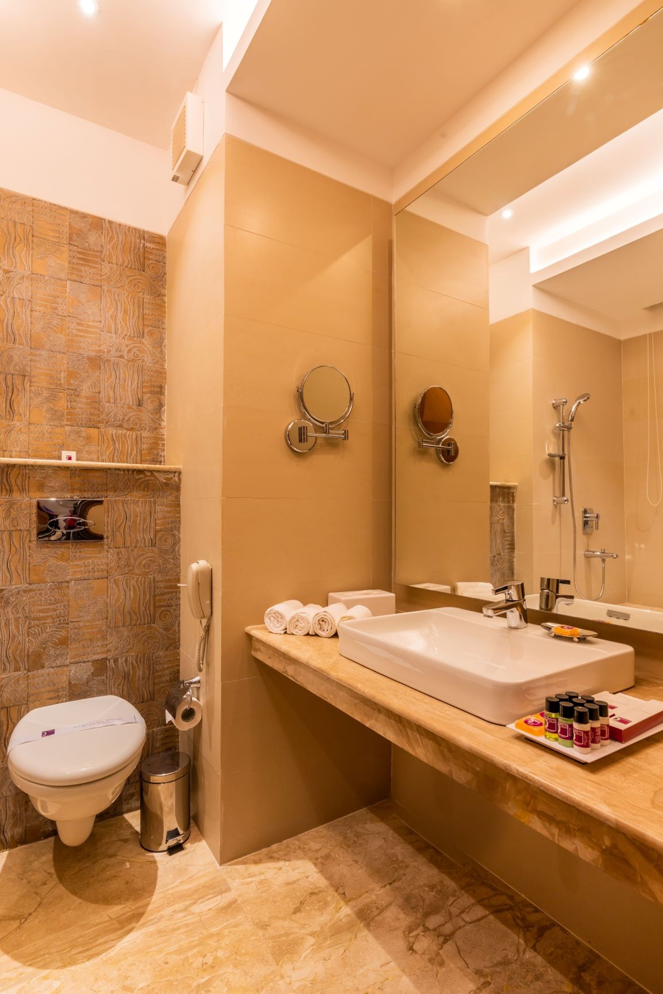 Une salle de bain moderne avec un grand miroir, une baignoire et des toilettes.