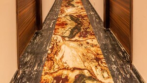 A long, narrow hotel corridor with wooden doors on both sides, a patterned carpet, and a ceiling with recessed lighting. - Divine Clarks Inn Suites (Thanesar)