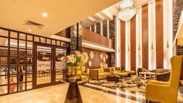 A lobby with a seating area, a reception desk, and a large window. - Divine Clarks Inn Suites (Thanesar)