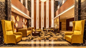 A lobby with a central seating area, a chandelier, and a patterned carpet. - Divine Clarks Inn Suites (Thanesar)
