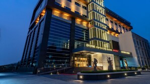 A modern hotel with a prominent entrance, multiple floors, and illuminated signage. - Divine Clarks Inn Suites (Thanesar)