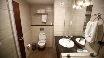 Un baño moderno con inodoro, lavabo, espejo, toallero y un cubo de basura.