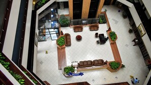 A hotel lobby with a central seating area, a reception desk, and a staircase.