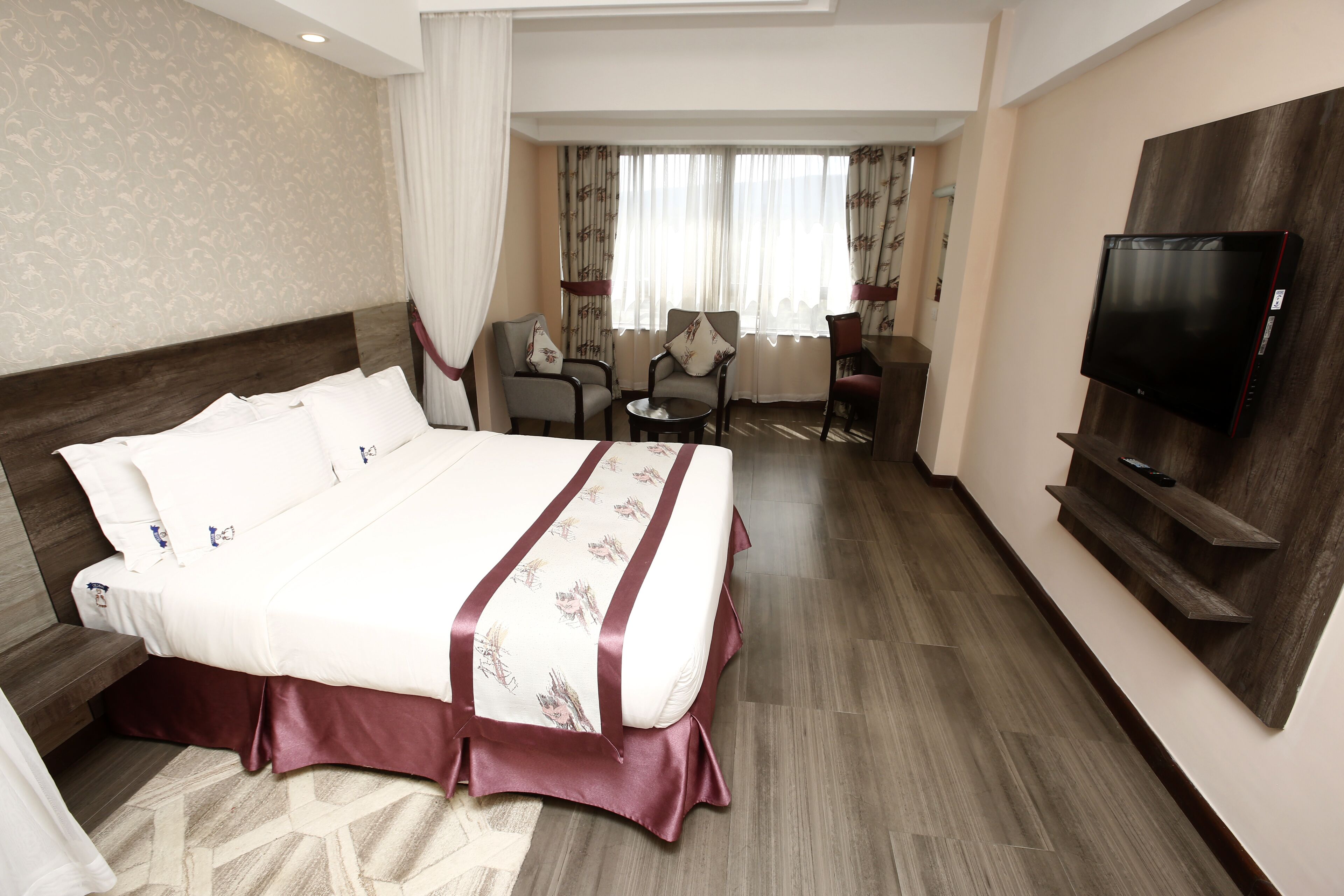 A hotel room with a large bed, a television, a desk, and a chair.