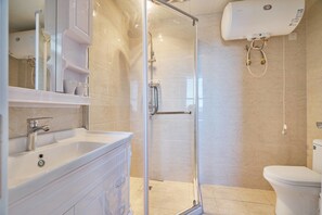 Un baño moderno con ducha de vidrio, lavamanos blanco y retrete.