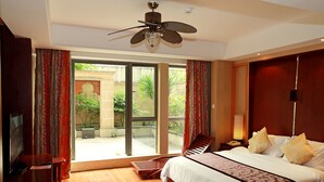 Une chambre d’hôtel équipée d’un lit, d’un bureau, d’une chaise, d’un ventilateur de plafond et offrant une vue sur l’extérieur.