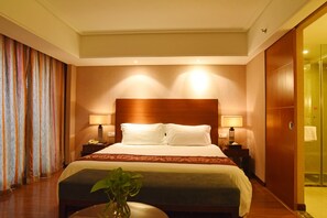 A hotel room with a large bed, two bedside tables with lamps, a bedside plant, and a view of the bathroom. - Nan He Xi Yue Hotel (Chengdu)