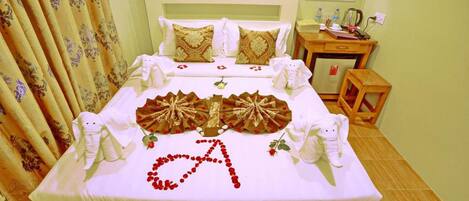 A neatly made bed with a decorative arrangement of flowers spelling 'A' and a wooden headboard.