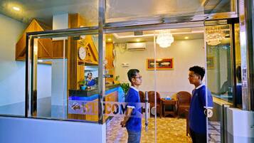 A reception area with a 'WELCOME' sign, a receptionist, and a counter.