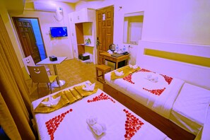 A hotel room with two beds, a desk, a chair, a television, and a door. - Hotel Aurora (Mandalay)