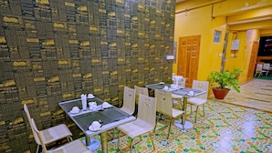 A restaurant with tables and chairs, a patterned wall, and a tiled floor. - Hotel Aurora (Mandalay)