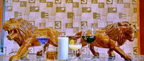 Una zona de bar con dos estatuas de león, una copa de martini, una copa de leche y una copa de vino.