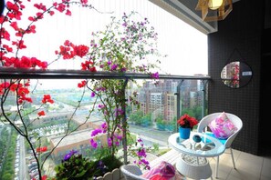 Un balcone con vista sulla città, una pianta in vaso e una sedia.