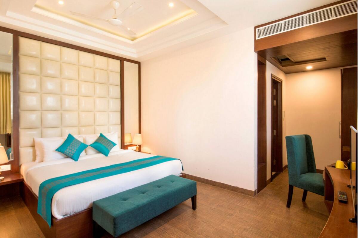 A hotel room with a large bed, a bench, a desk, and a chair.
