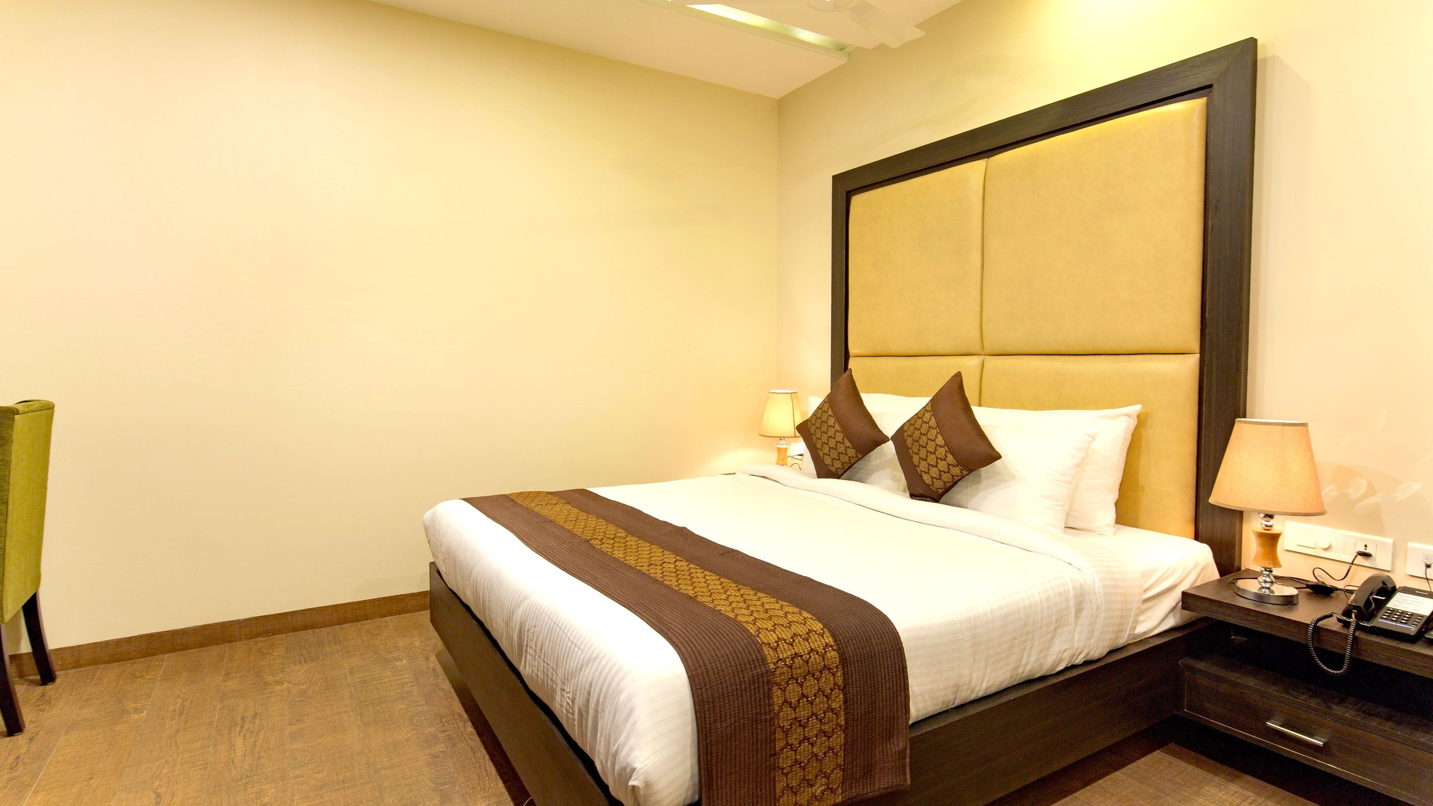 Una habitación de hotel con una cama grande, mesitas de noche, una lámpara y un teléfono.