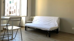 A room with a bed, a chair, a table, and a window with an open shutter. - Termini Station Little House (Rome)