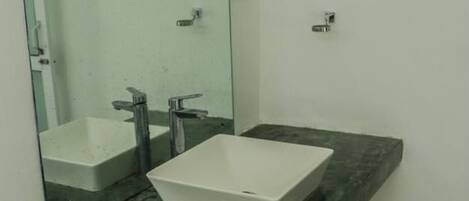 Un baño con un espejo grande, dos lavamanos y una encimera de mármol verde.