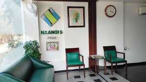 A room with a green sofa, two green chairs, a small table with a magazine, a clock, and a framed picture on the wall. - Nangi's Pride (Jaipur)