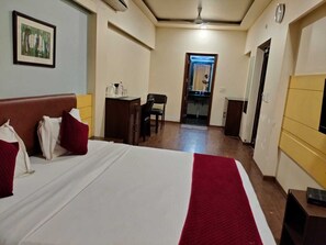 A hotel room with a bed, a desk, a chair, and a small kitchenette. - Nangi's Pride (Jaipur)