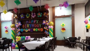A room with a birthday banner, balloons, and a table set for a celebration. - Nangi's Pride (Jaipur)