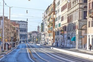 A street with tram tracks, buildings with balconies, and a clear sky. - Friendly Domus al Colosseo (Rome)