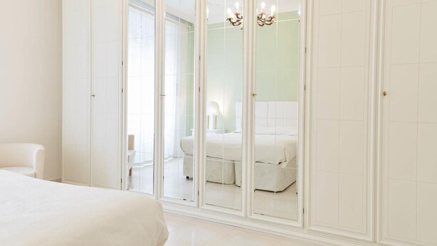 A bedroom with a large wardrobe, a bed, and a chair. - Flaminio & Popolo Large Apartment (Rome)