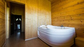 Relax in a spacious room with a large bathtub and wooden floor.