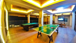 Un amplio espacio interior con mesa de ping pong, mesa de billar y mesa de futbolín.