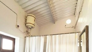 A small, basic bathroom with a toilet, a sink, and a shower curtain. - Laika Heritage Stay by evaddo stays (Mysore)