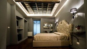 A bedroom with a large bed, built-in shelving, a skylight, and a decorative headboard. - Il Covo (Rome)