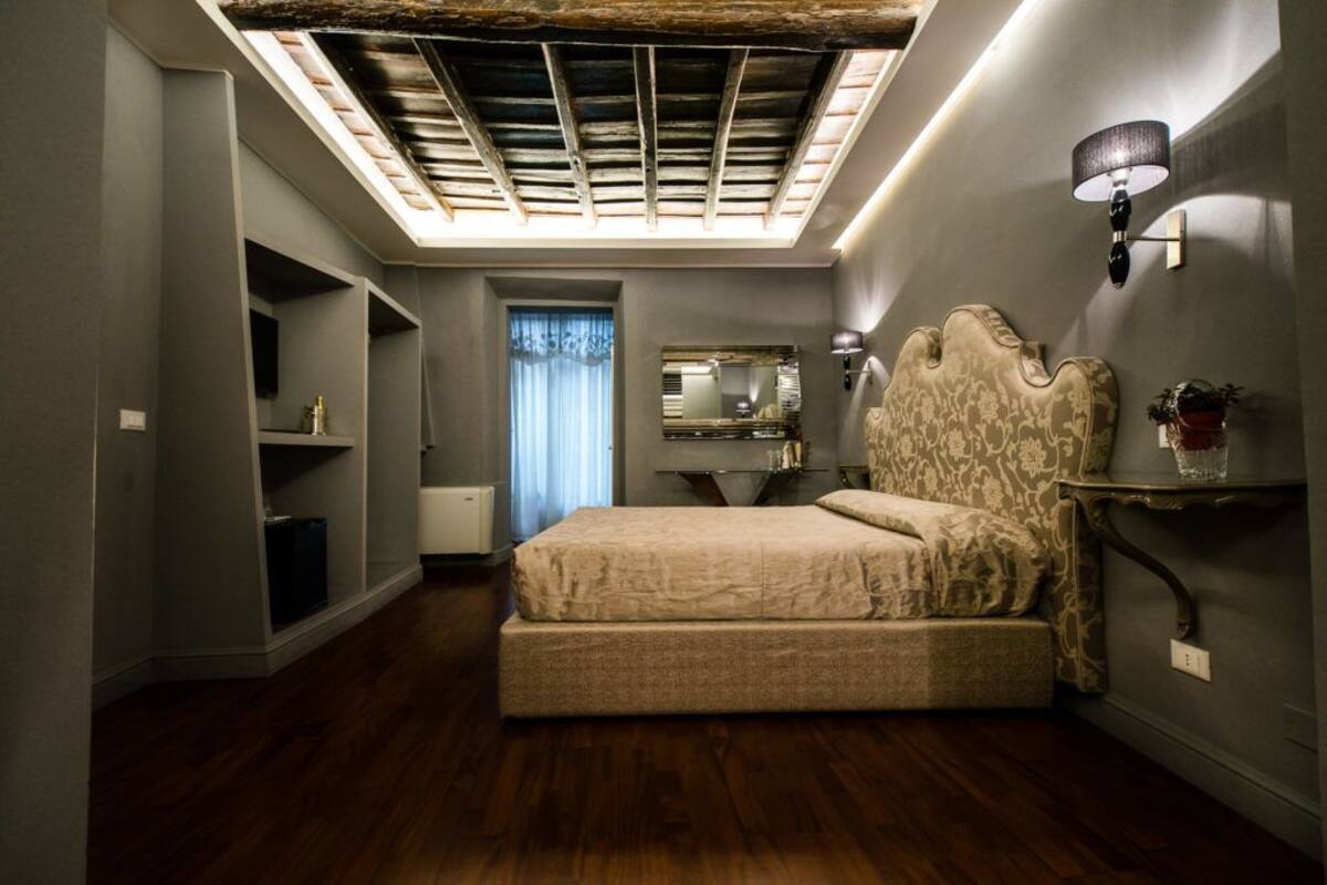 A bedroom with a large bed, built-in shelving, a skylight, and a decorative headboard.