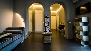 A modern hallway with a sofa, a decorative wall piece, and a staircase leading to another room. - Il Covo (Rome)