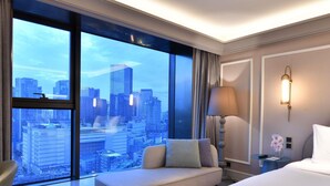 A hotel room with a large window offering a city view, a sofa, a bed, and a nightstand with a lamp. - Mercure Chengdu Chunxi Taikoo Li (Chengdu)