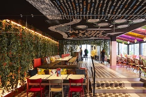 Een restaurant binnen met een groene wand, een geruit vloertje en een plafond met tekst en patronen.