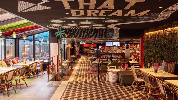 Un restaurante con piso a cuadros, mobiliario de mimbre y un techo con mensajes inspiradores.