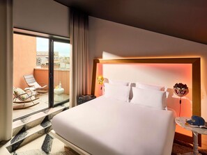 Ein Hotelzimmer mit einem großen Bett, einem Balkon mit Sitzgelegenheiten und Blick auf die Stadt.