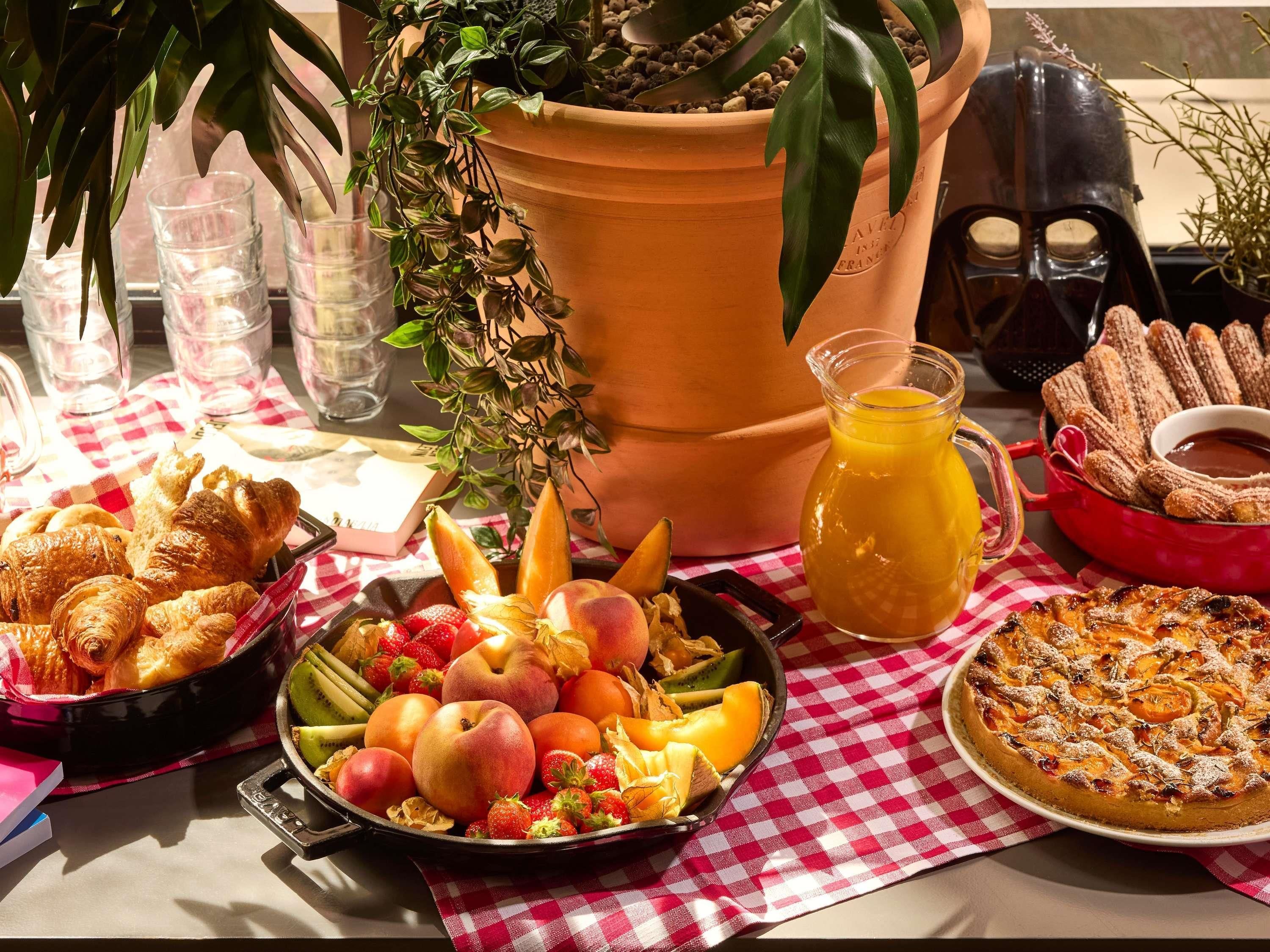 A breakfast table with pastries, fruit, and a fruit tart.