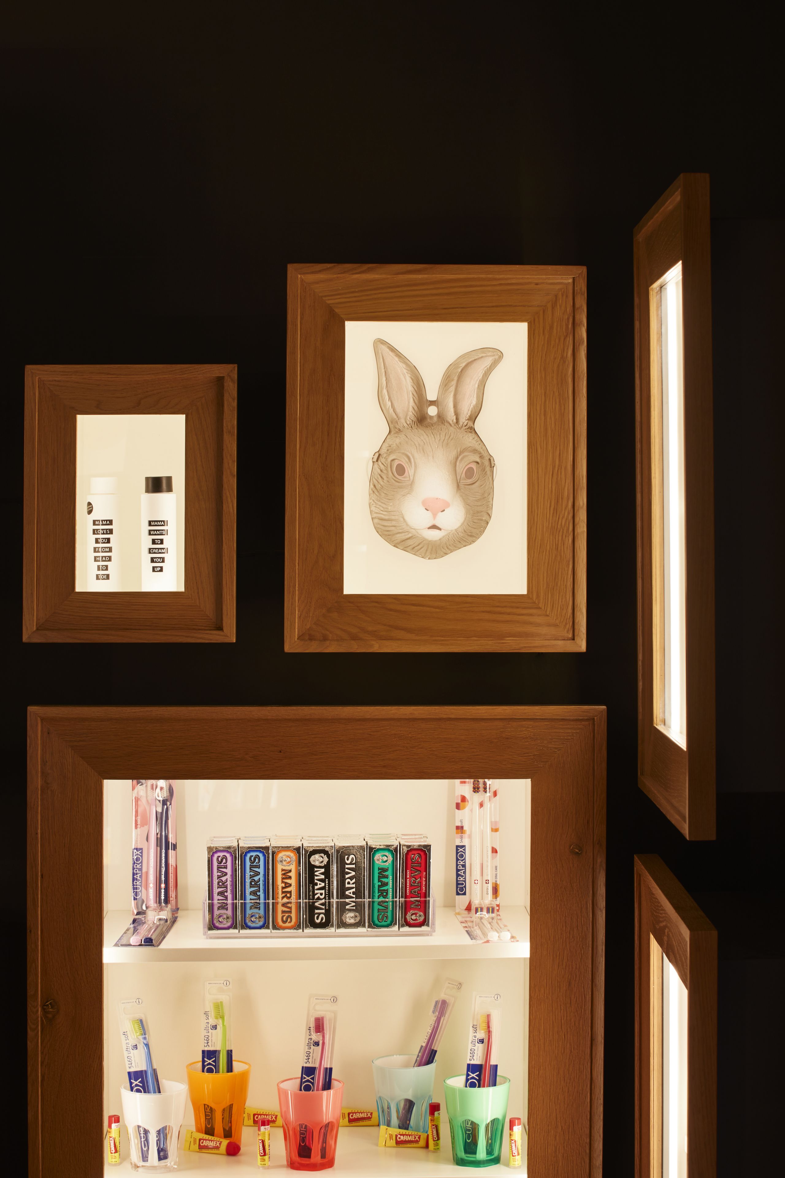 A wall with framed artwork and shelves displaying various products.