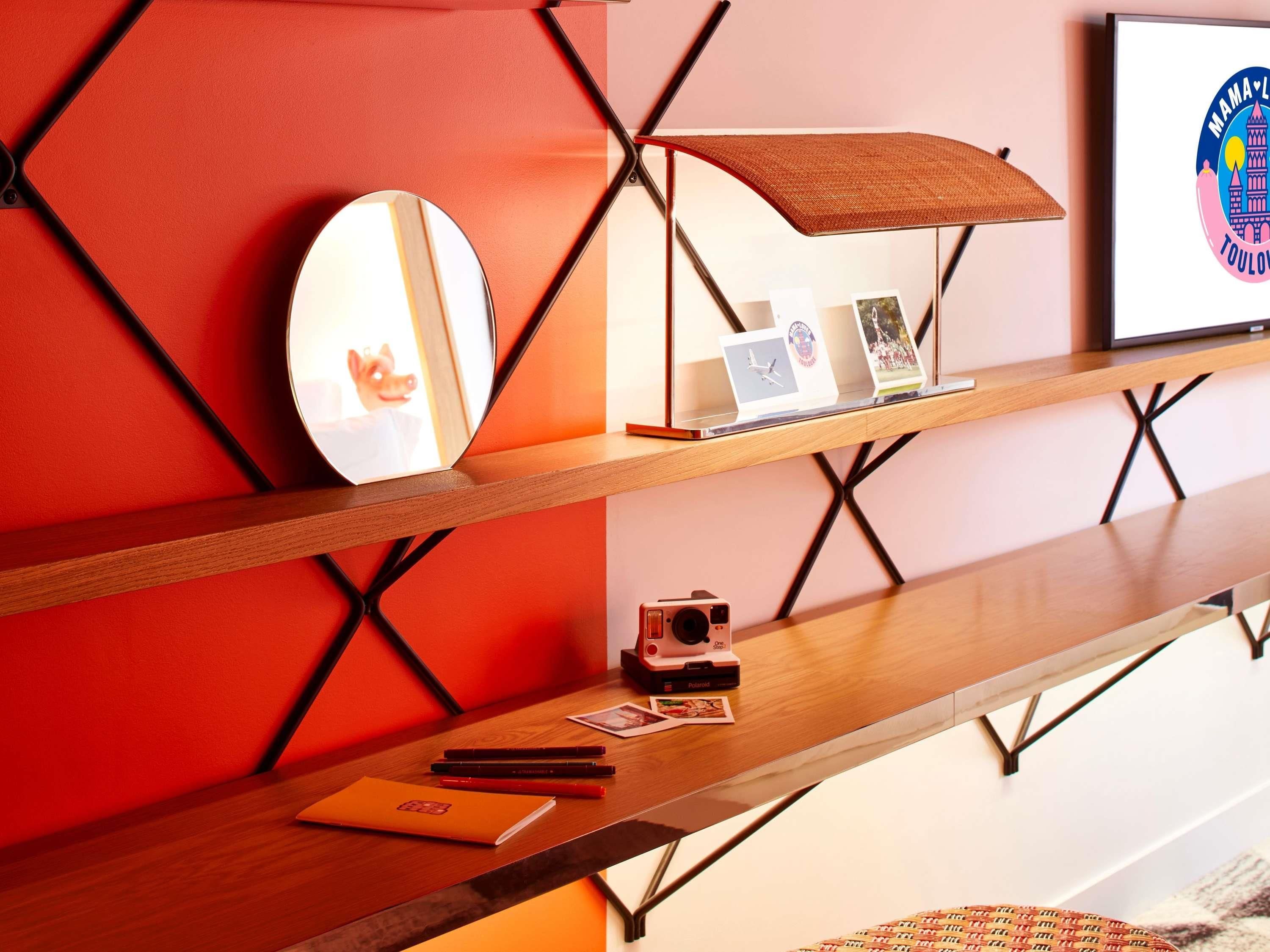 Un intérieur moderne avec un bureau en bois, un miroir, un appareil photo Polaroid et un logo encadré.
