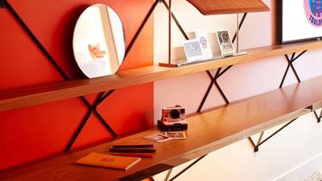 A modern interior with a wooden desk, a mirror, a Polaroid camera, and a framed logo.