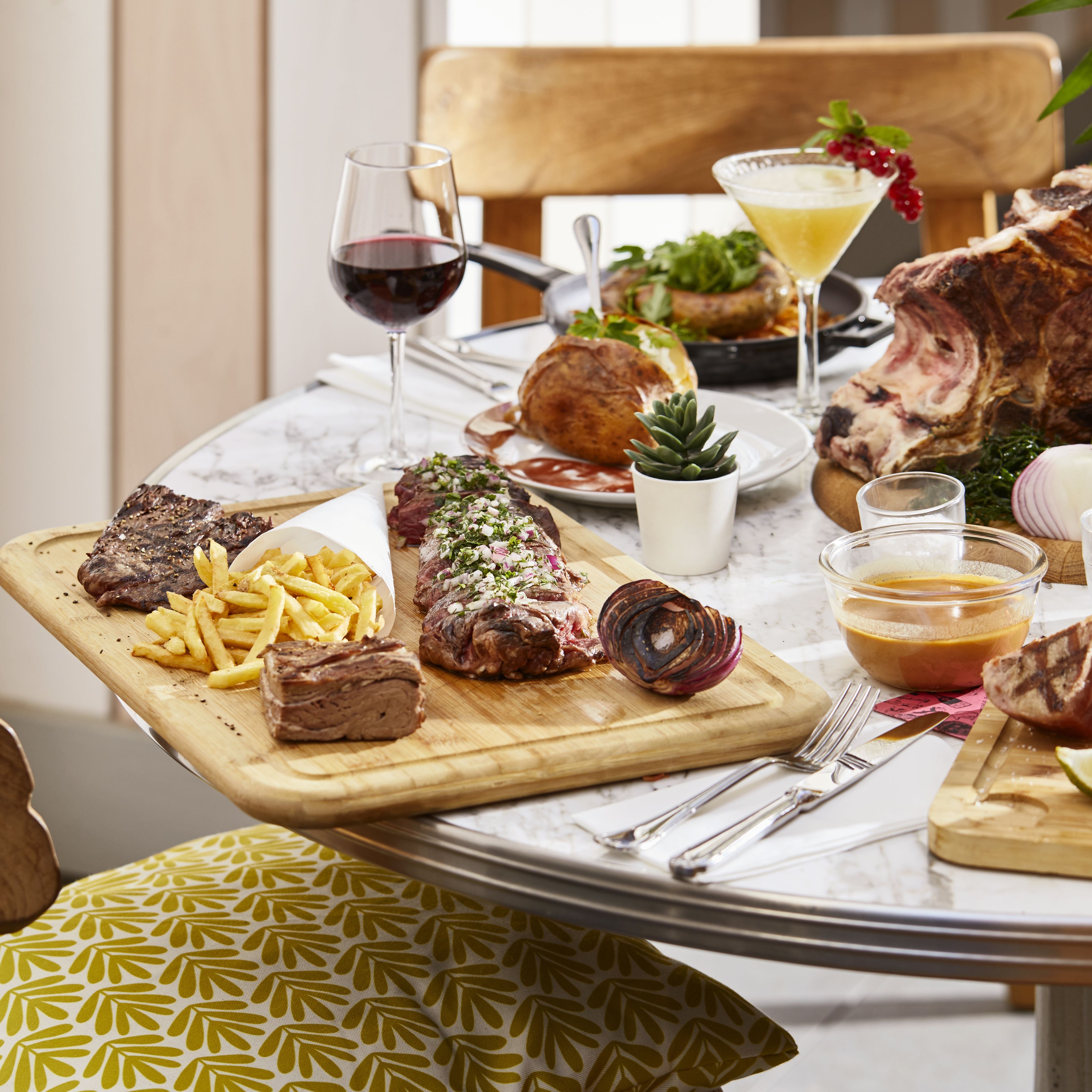A dining table with various dishes including steak, fries, and a salad.