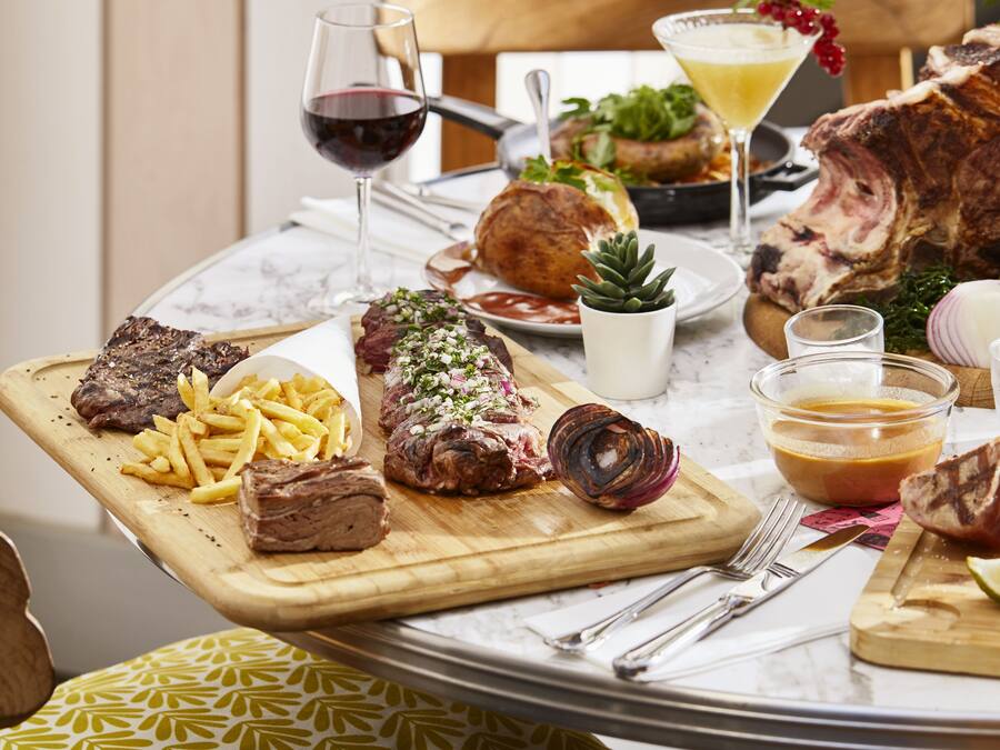 A dining table with various dishes including steak, fries, and a salad.
