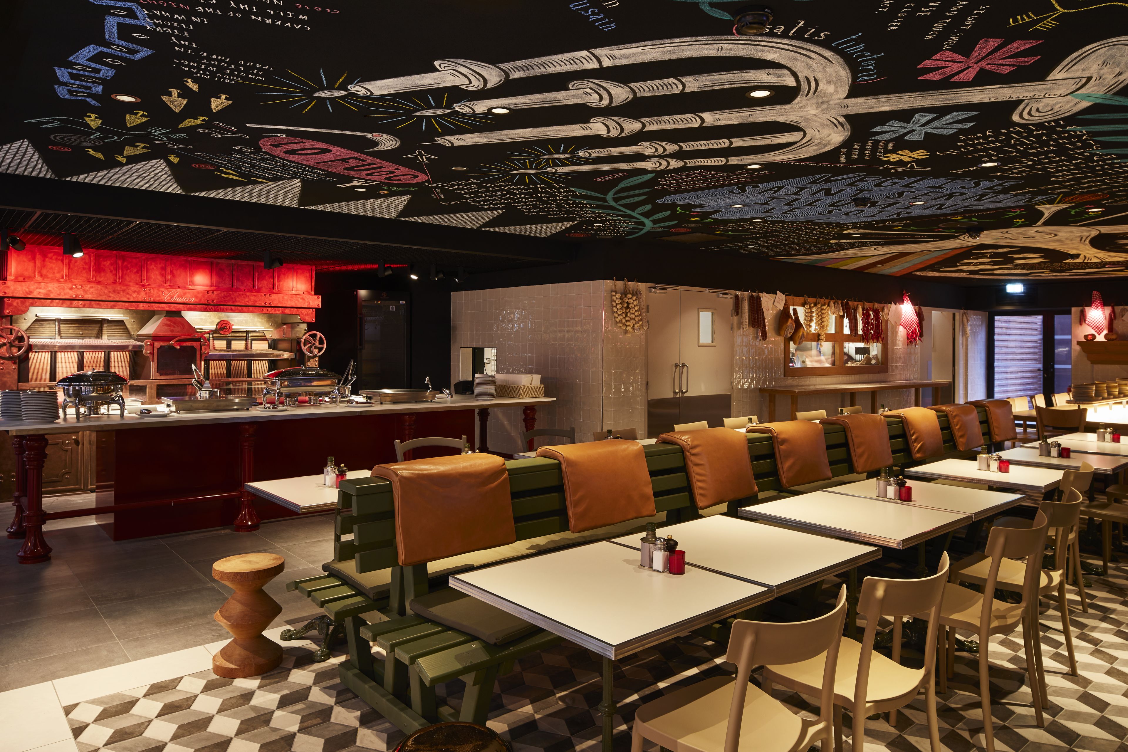 A restaurant with booths and tables, a bar area, and a ceiling with artistic designs.